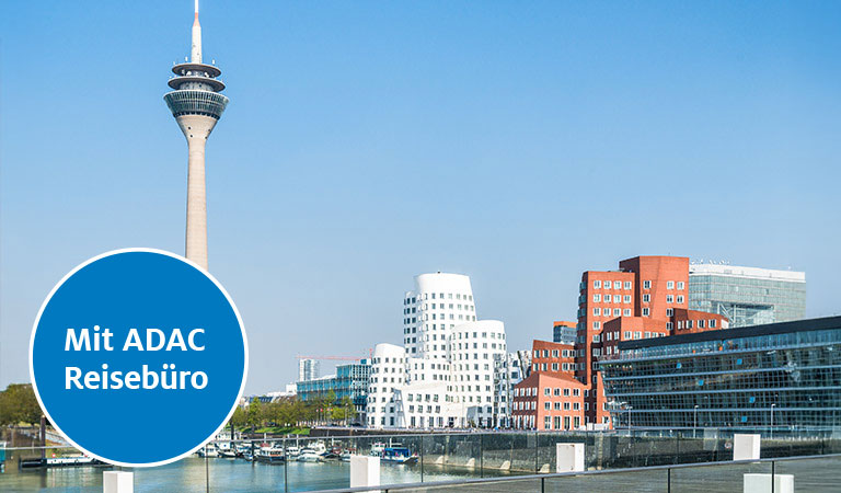 Skyline von Düsseldorf mit Rheinturm, modernen Gebäuden und blauem Himmel.
