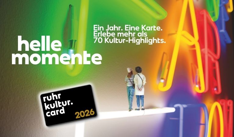 Zwei Personen betrachten bunte Leuchtschrift an der Wand und wirken nachdenklich