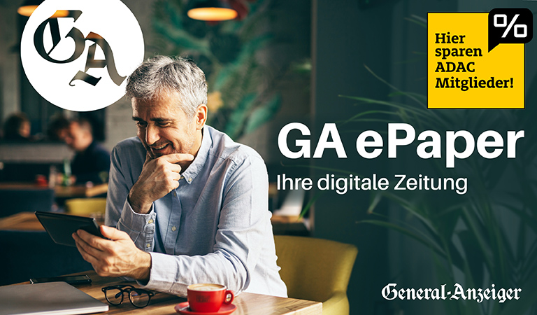Ein lächelnder Mann mit grauem Haar sitzt in einem Café und liest ein Tablet.