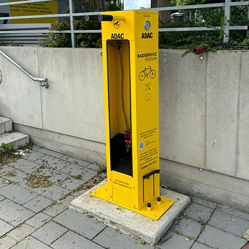 Gelbe ADAC Radservice-Station mit Werkzeugen im Freien, graue Umgebung, keine Personen sichtbar.