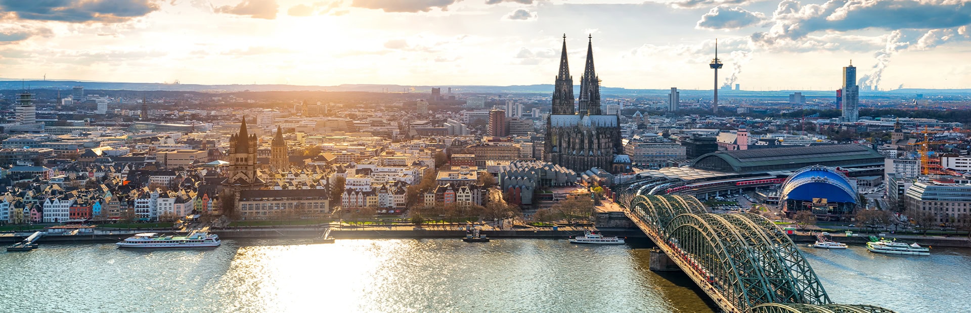 Panorama von Köln mit dem Dom, der Hohenzollernbrücke und Rhein im Sonnenuntergang.
