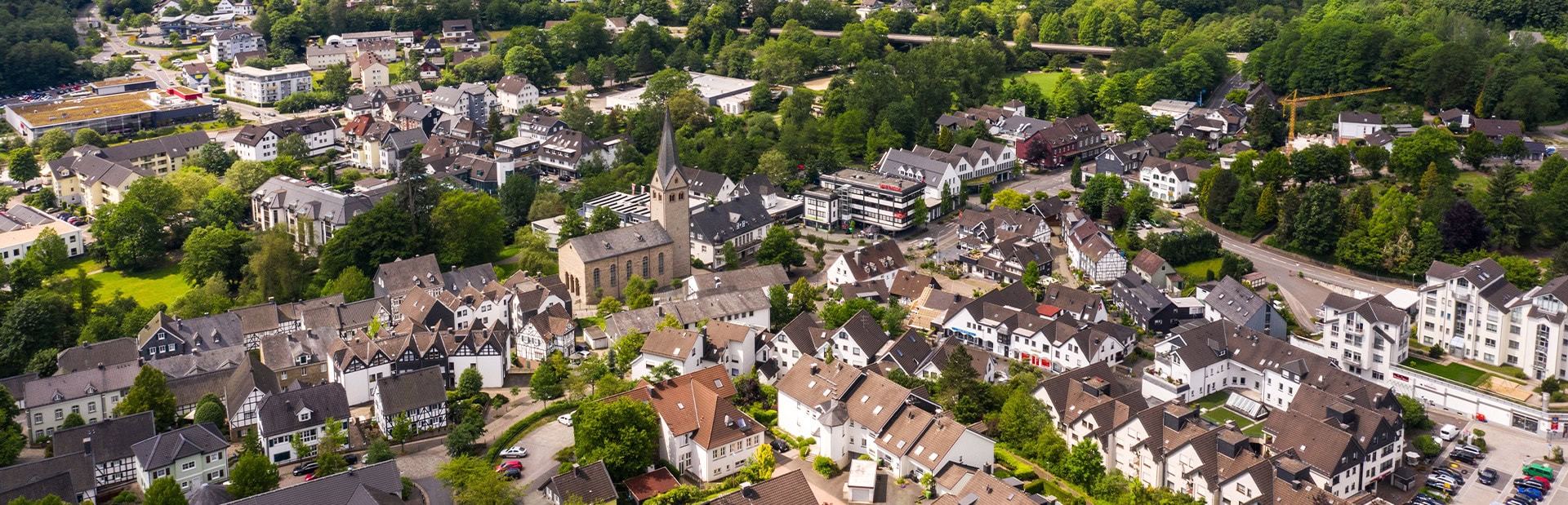 Luftaufnahme einer deutschen Stadt mit vielen Häusern, einer Kirche und umgeben von grünen Bäumen.