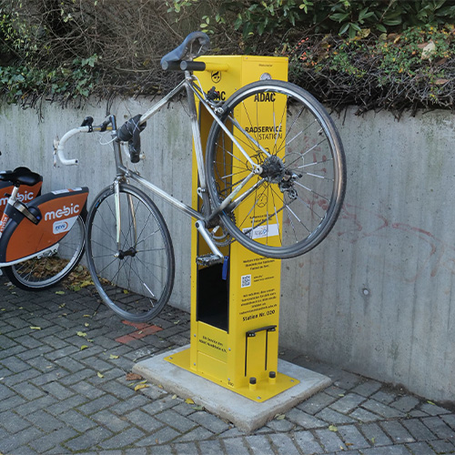 Fahrrad auf gelber Reparatursäule montiert, mit Hinterrad in der Luft, neben ADAC-Logo.