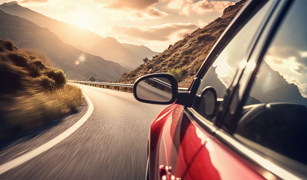 Rote Autotür beim Fahren durch malerische kurvenreiche Bergstraßen.