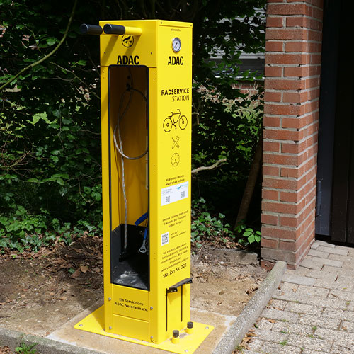 Gelbe Fahrrad-Servicestation von ADAC mit Werkzeugen im Freien.