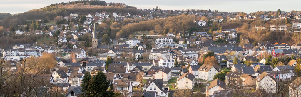 Eine Stadtlandschaft voller Häuser mit Hügeln und Bäumen im Hintergrund