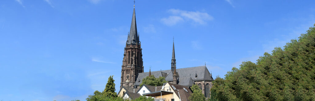 Eine beeindruckende Kirche mit hohen Türmen überragt umliegende Bäume.