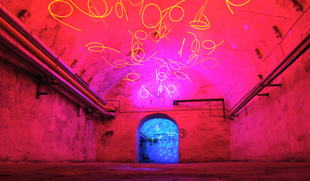 Ein leerer, pink beleuchteter Tunnel mit leuchtenden gelben Lichtmustern an der Decke