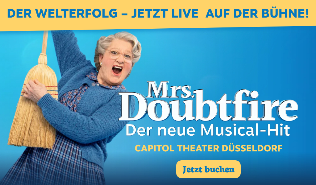 Eine ältere Frau mit breitem Lächeln, Brille und blauem Pullover schwingt einen Besen