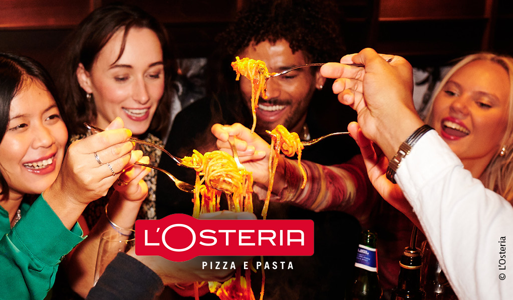 Vier fröhliche Menschen genießen gemeinsam Spaghetti in einem warm beleuchteten Restaurant