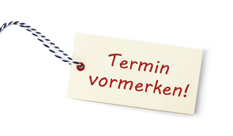 Bunte Häuser und eine grüne Kirche mit Turm stehen unter blauem Wolkenhimmel