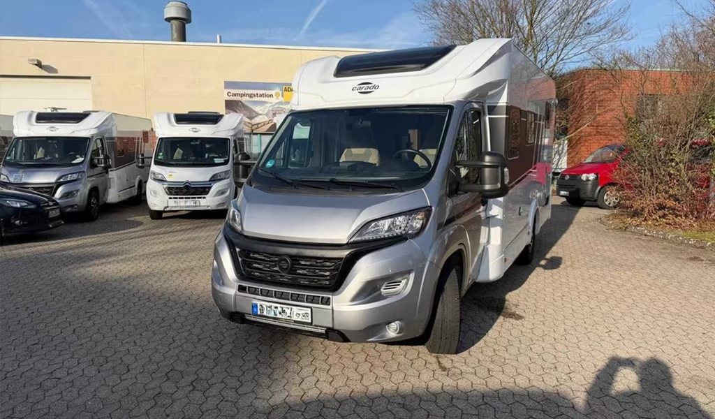 Ein silberner Wohnwagen mit schwarzen Akzenten steht auf einem gepflasterten Hof