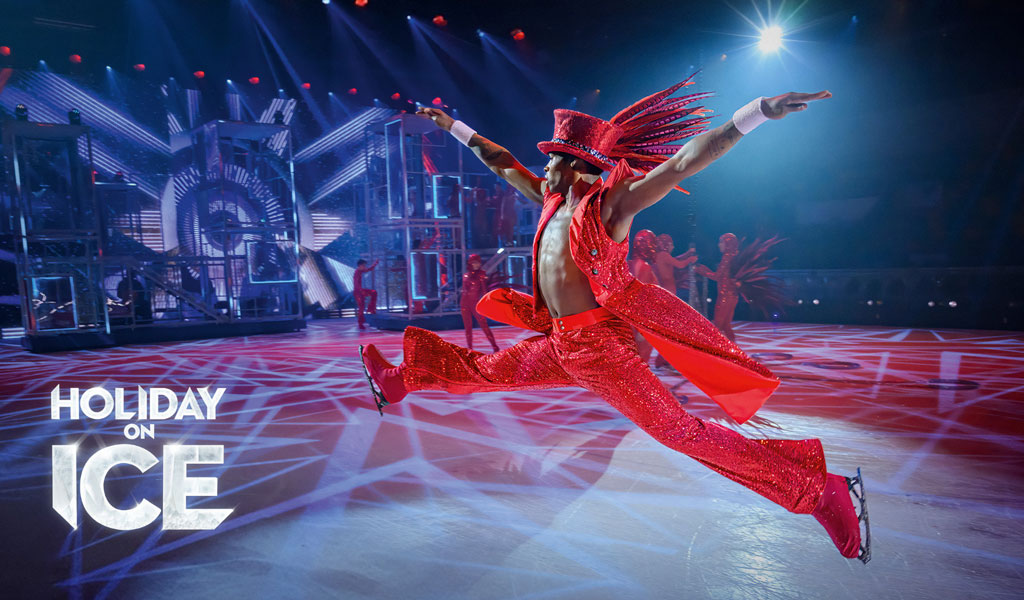 Eine Person in auffälligem roten Glitzerkostüm springt energisch auf dem Eis