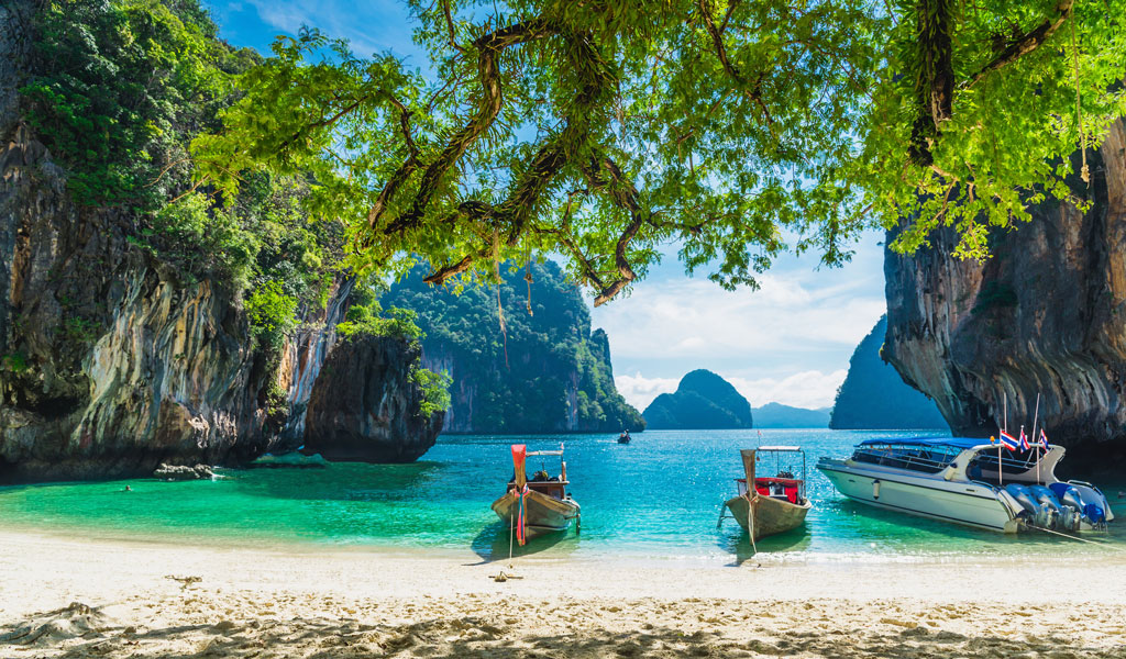 Ein roter Leuchtturm steht auf einer grünen Düne an einem ruhigen Sandstrand
