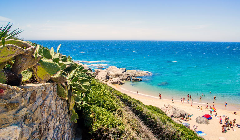 Bunte Häuser und eine grüne Kirche mit Turm stehen unter blauem Wolkenhimmel