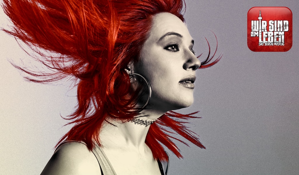 Frau mit leuchtend roten Haaren und auffälligen Ohrringen schaut entschlossen