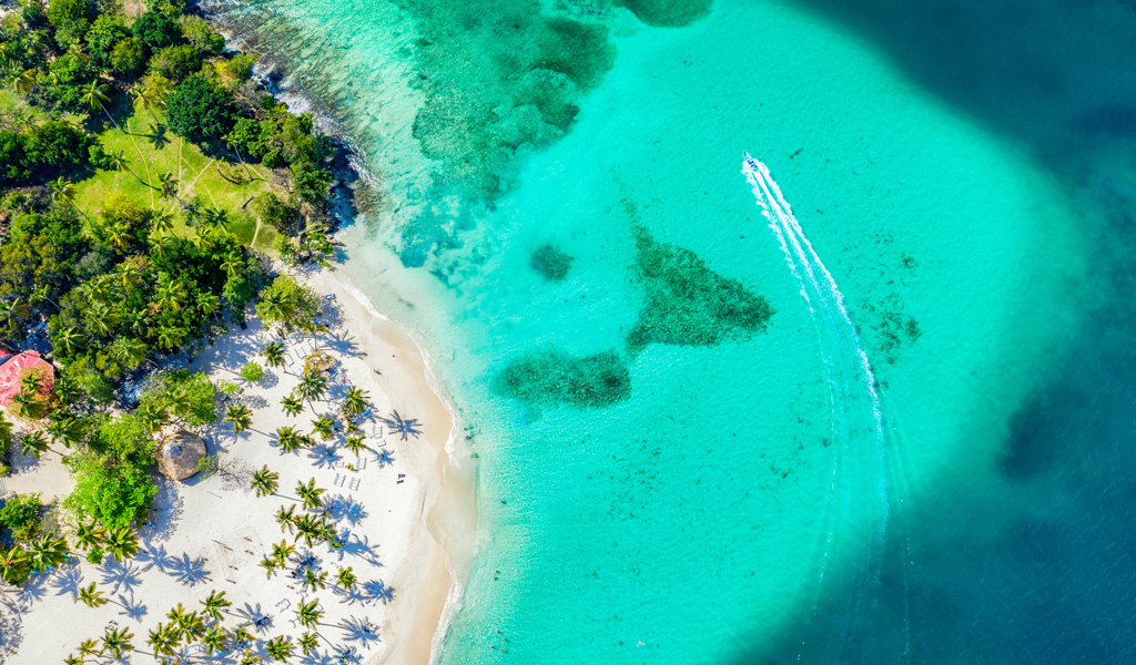 Ein roter Leuchtturm steht auf einer grünen Düne an einem ruhigen Sandstrand