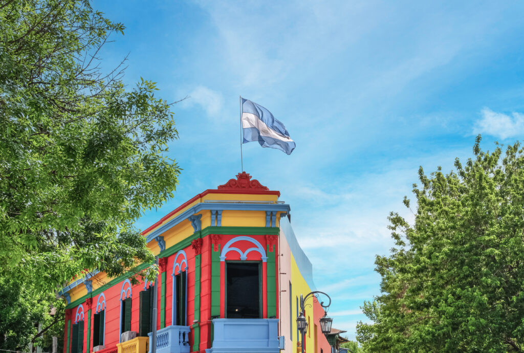 Eine bunte Fassade mit roten und grünen Details zeigt eine wehende Flagge