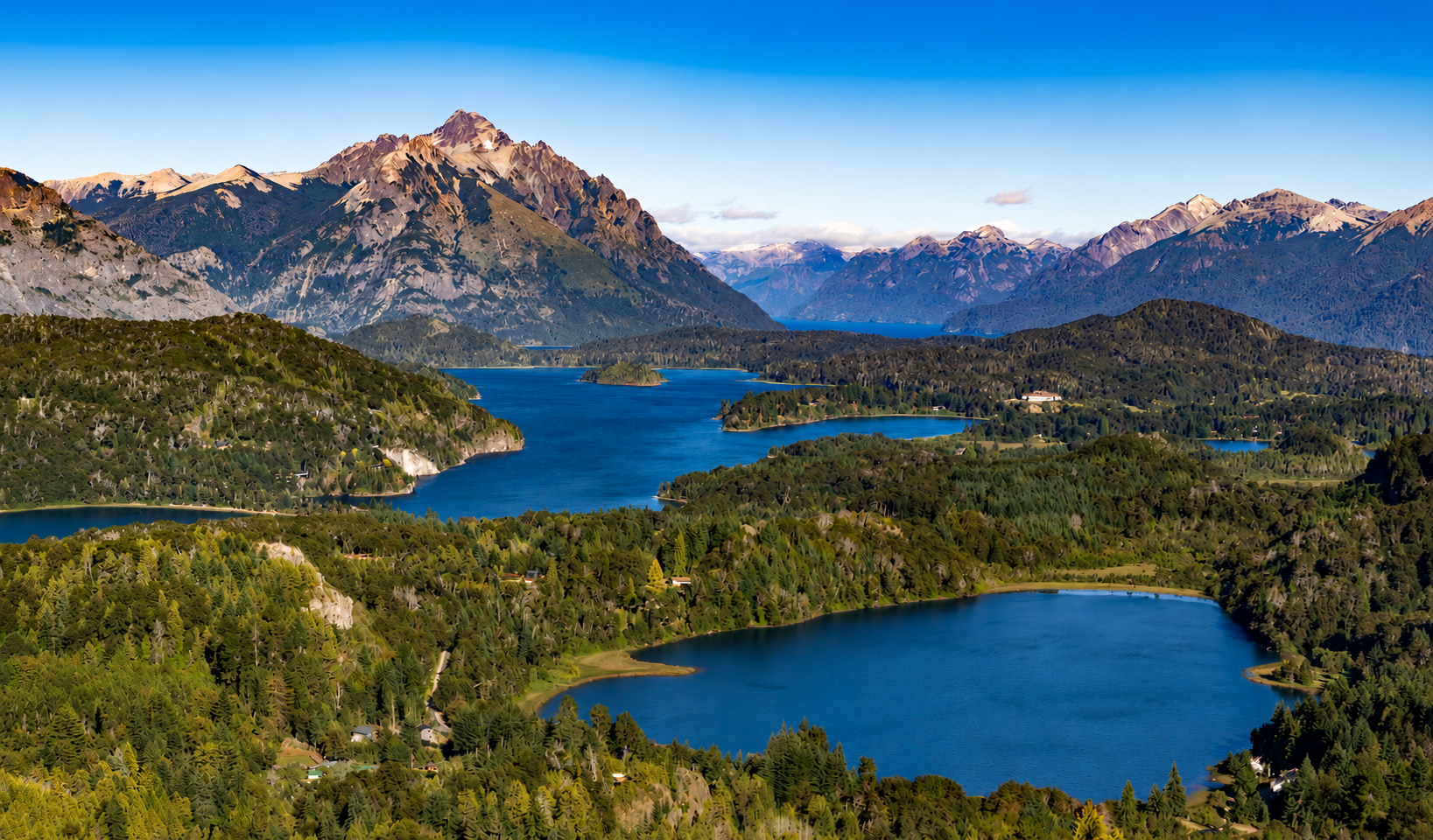 Blauer See inmitten grüner Hügel und Berge unter strahlend klarem Himmel