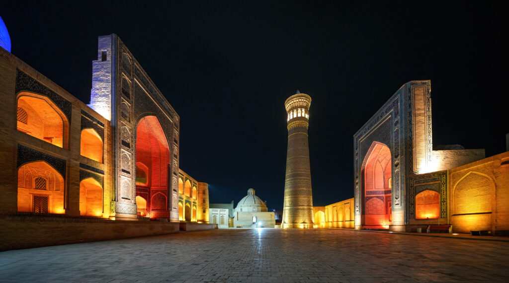Ein nächtlicher Blick auf beleuchtete historische Gebäude mit einem hohen Minarett.
