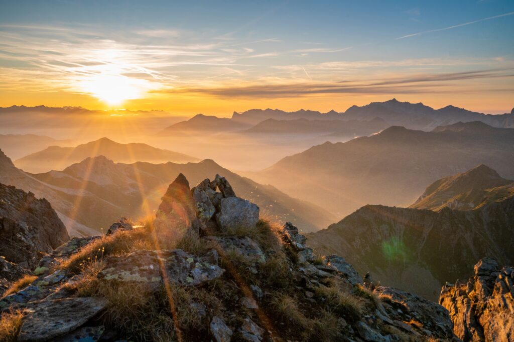 Sonnenaufgang über bergigen Landschaften mit goldenen Farbtönen und klarer Sicht