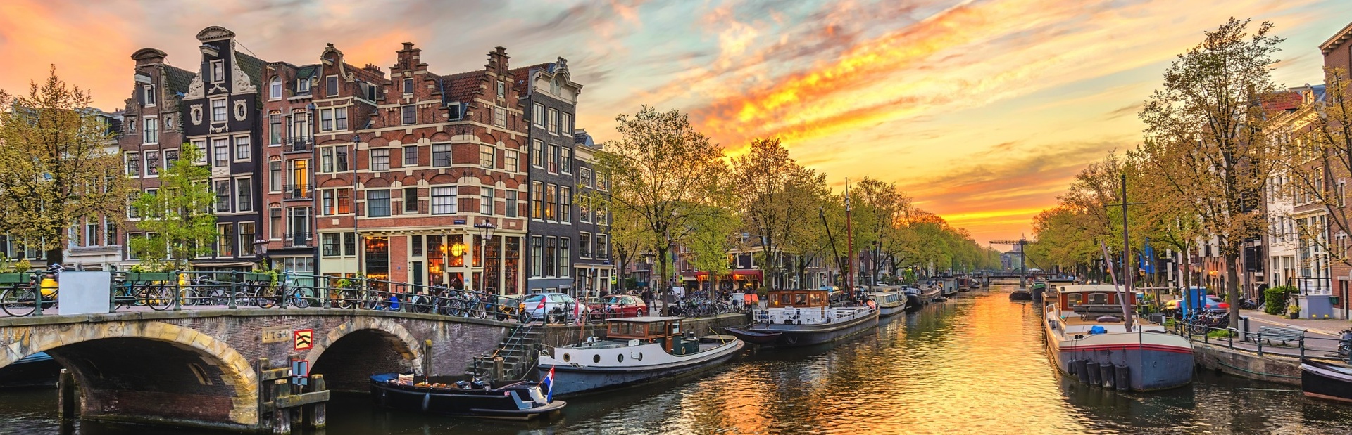 Lebhafter Sonnenuntergang über Amsterdams Kanal, Boote und farbige Häuser