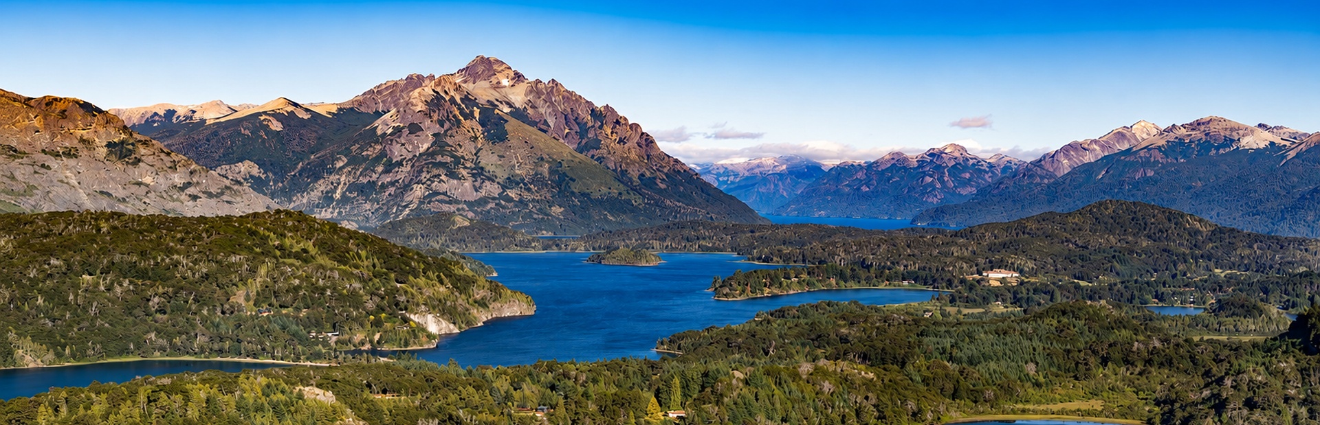 Eine ruhige Landschaft mit grünen Hügeln, blauem See und majestätischen Bergen im Hintergrund