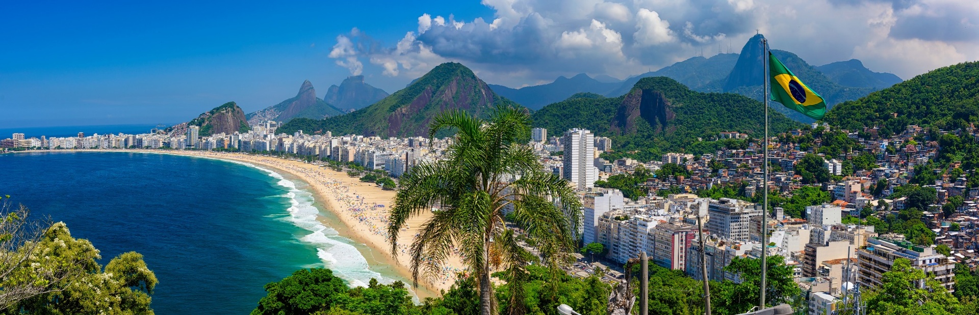 Panorama von Rio de Janeiro mit grüner Landschaft, gelbem Sandstrand und brasilianischer Flagge