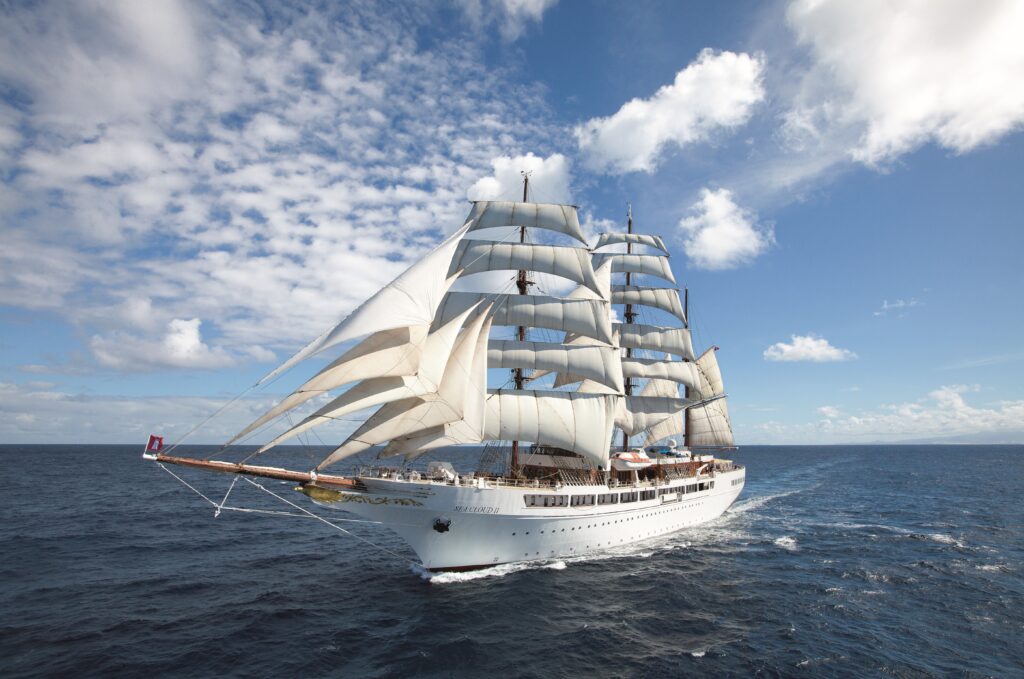 Ein weißes Segelschiff mit vielen großen Segeln fährt auf offenem blauen Meer