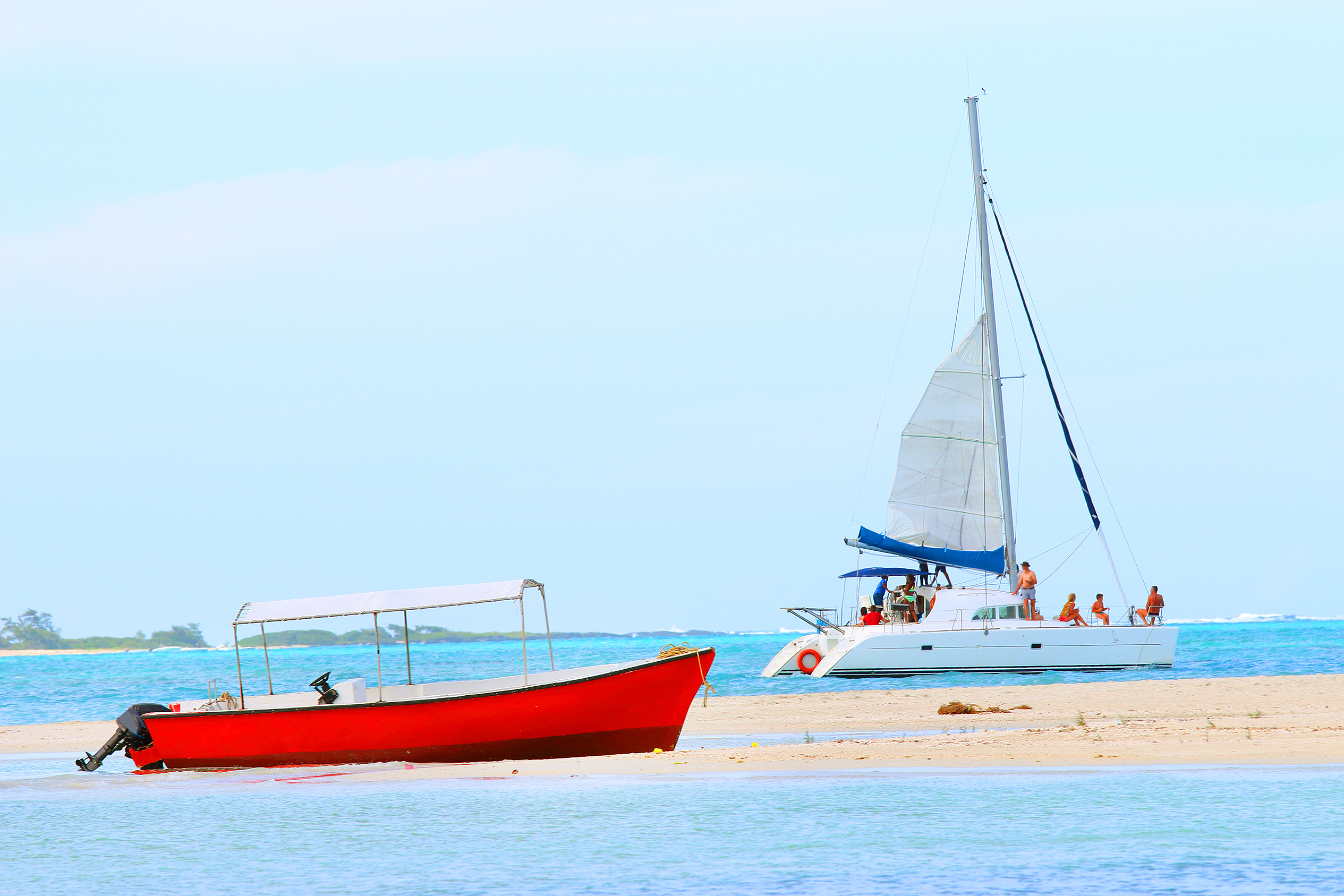 Ein rotes Boot und eine weiße Segelyacht mit entspannten Personen im blauen Wasser