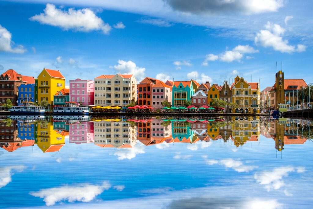 Bunte Häuser am Wasser spiegeln sich, lebendige Farben und klare Himmel mit Wolken