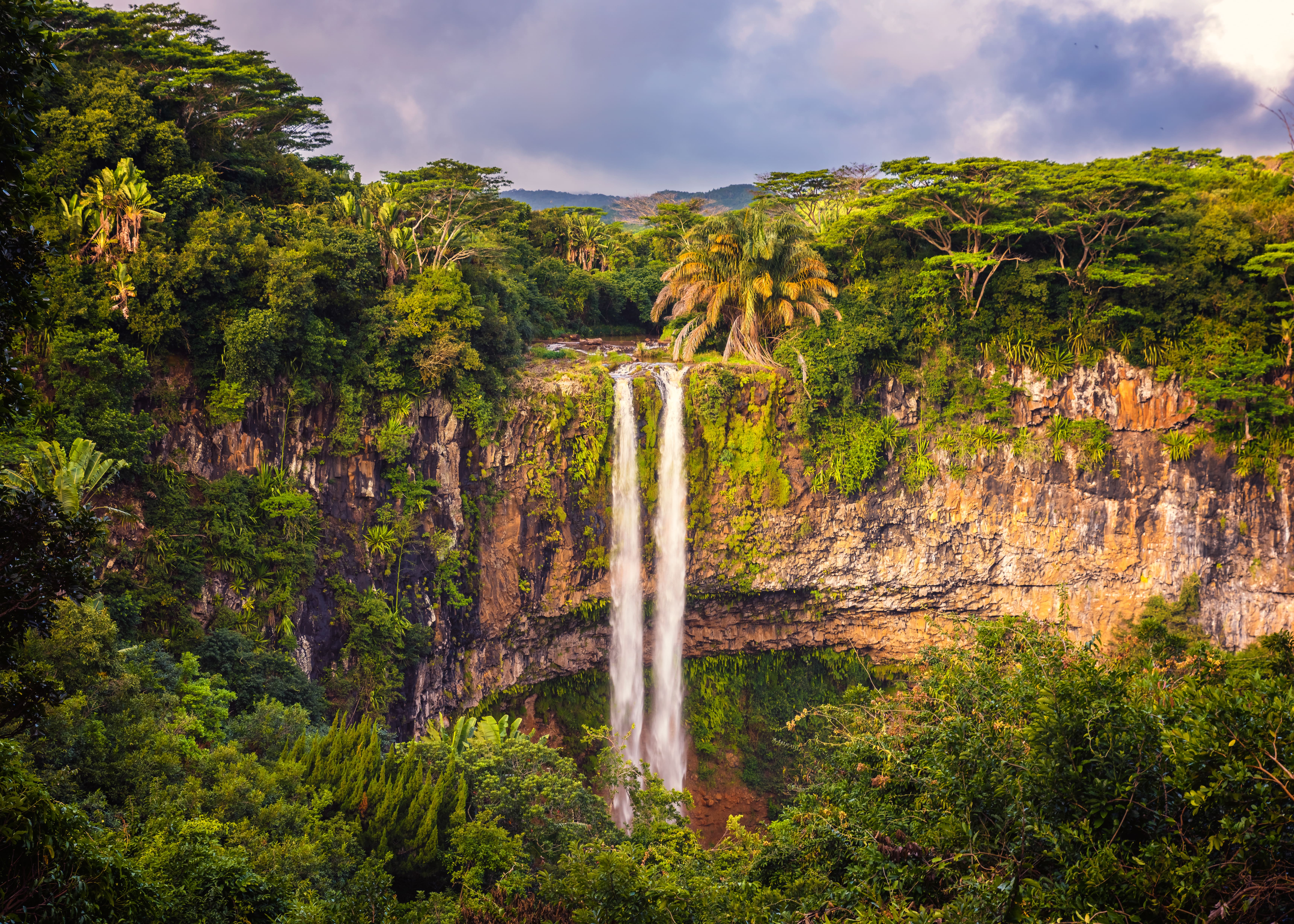 Ein hoher Wasserfall fließt durch üppige grüne Vegetation und felsige Klippen