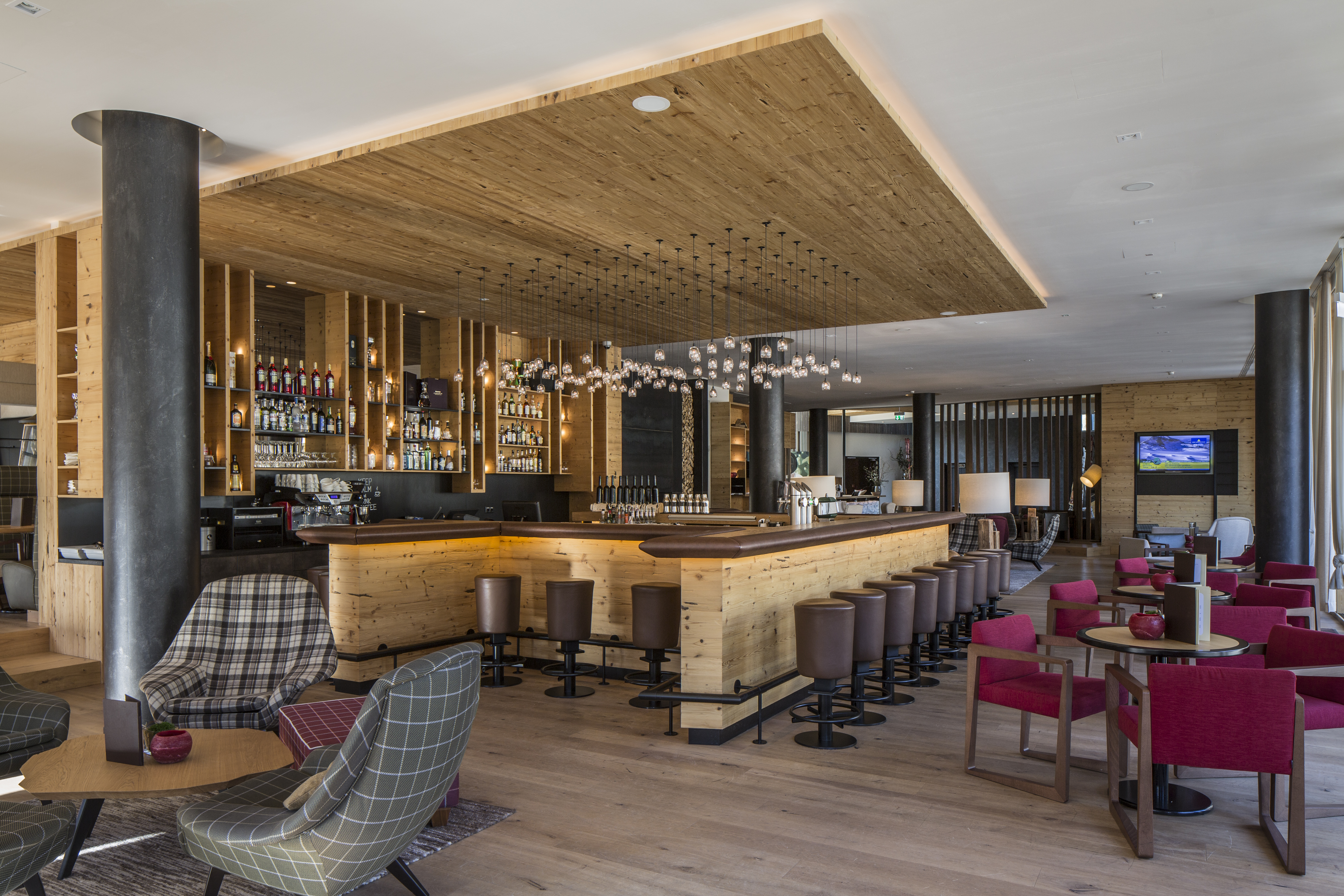 Eine moderne Bar mit Holzdecke und roten Sitzmöbeln, leer und hell beleuchtet