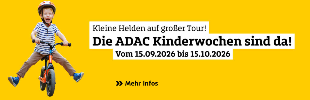 Ein fröhlicher Junge auf einem orangefarbenen Laufrad und gelbem Hintergrund