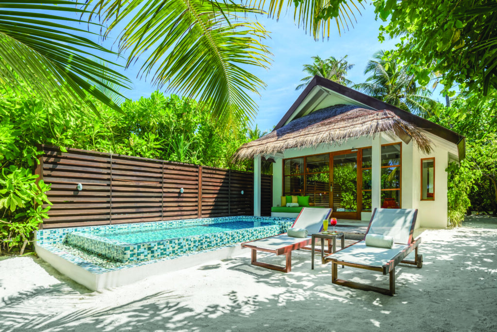 Eine luxuriöse Strandvilla mit Pool, Sonnenliegen und grüner tropischer Umgebung