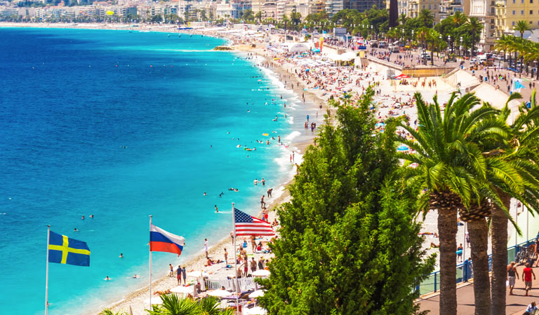 Menschen genießen einen sonnigen Tag am türkisblauen Strand mit Palmen und Flaggen