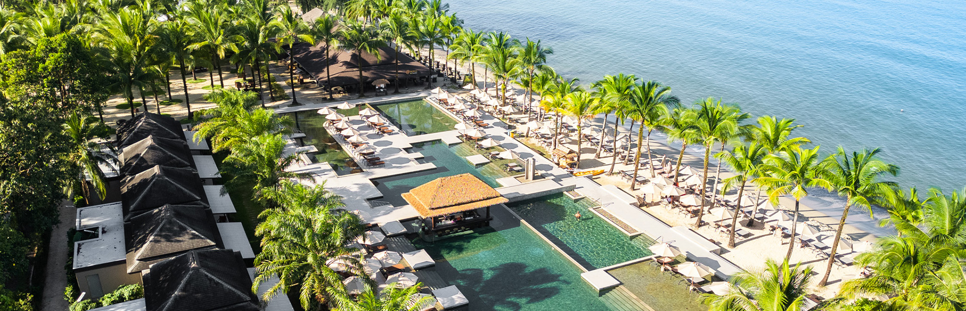 Luxuriöse Poolanlage mit grünen Palmen am Meer, entspannte Atmosphäre, sonnig