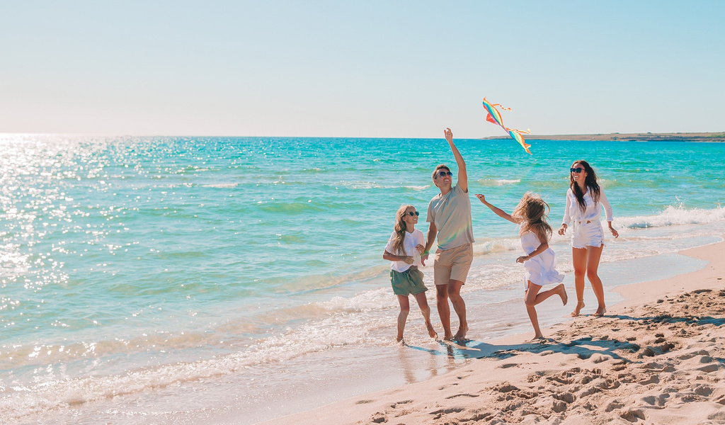 Eine Familie mit fröhlichen Gesichtern lässt einen bunten Drachen am Strand steigen
