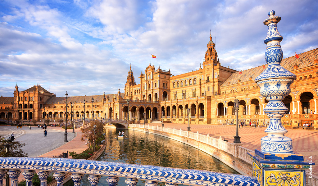 Die Plaza de Espana in Sevilla mit gelben Gebäuden, Wasserbecken und blauweißer Keramik
